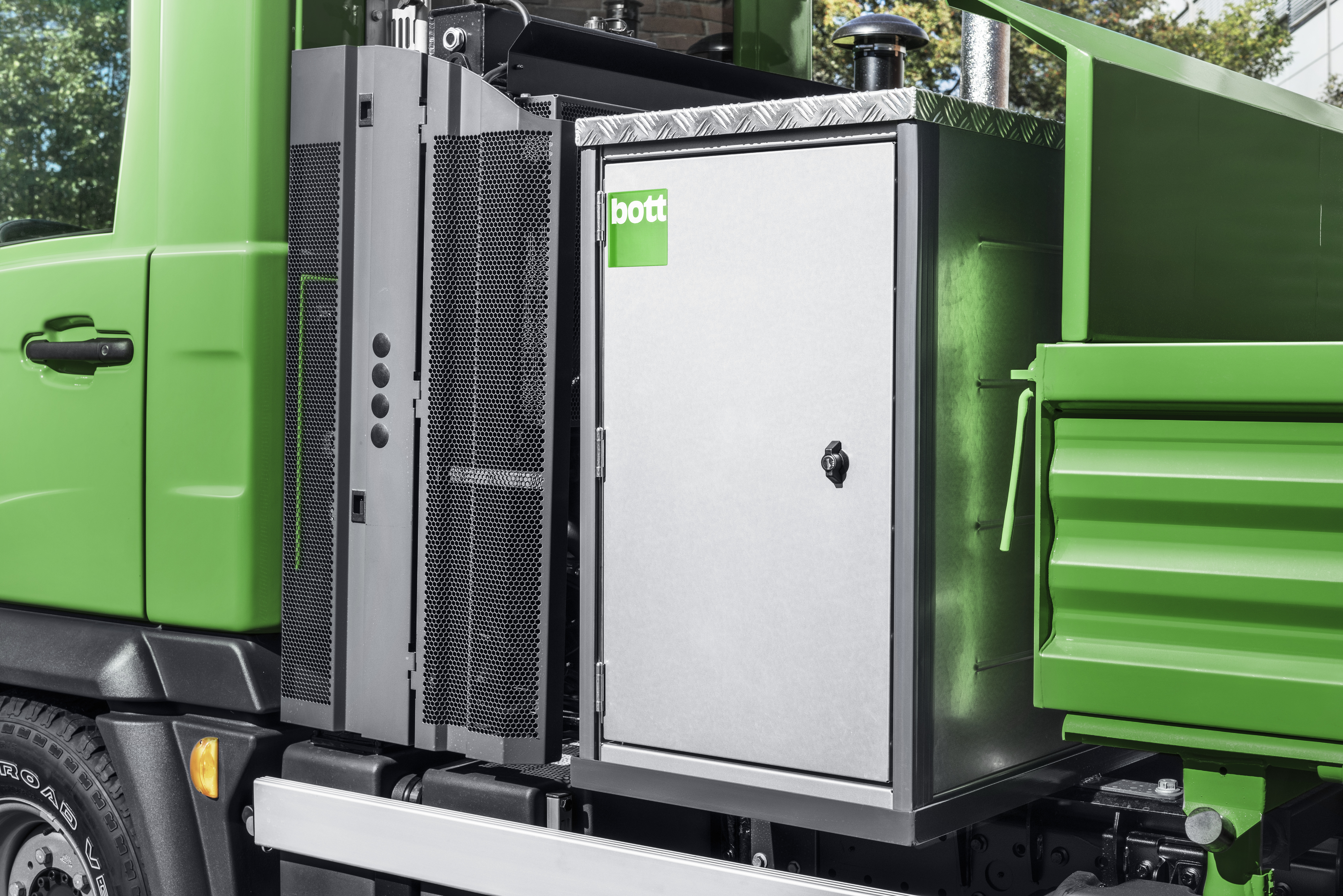 Green Multicar with a bottTainer, the flatbed body fully enclosed and secured with a lock
