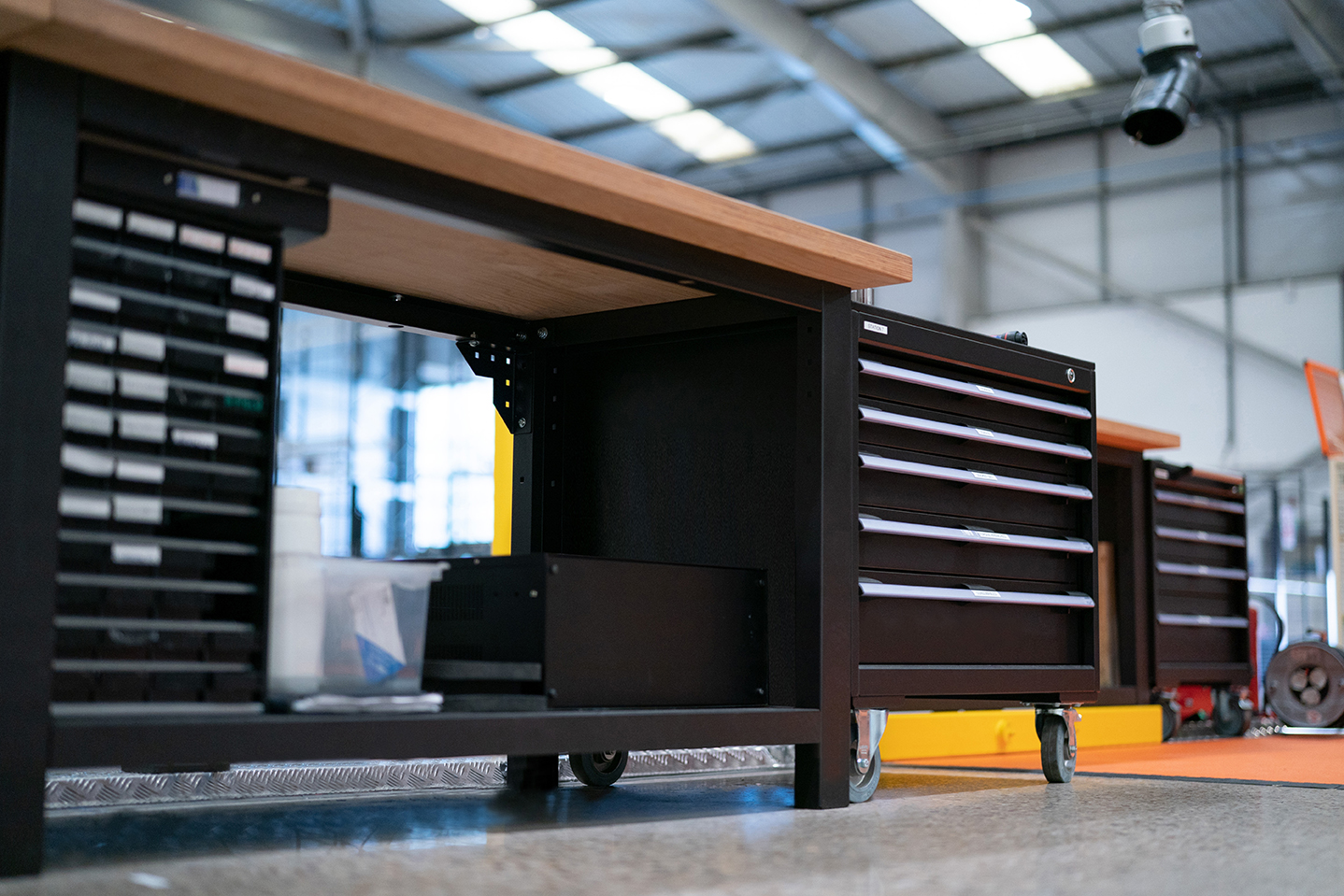 Multiplex worktop, made from hardwood, atop a black workbench and flexible storage in a warehouse.