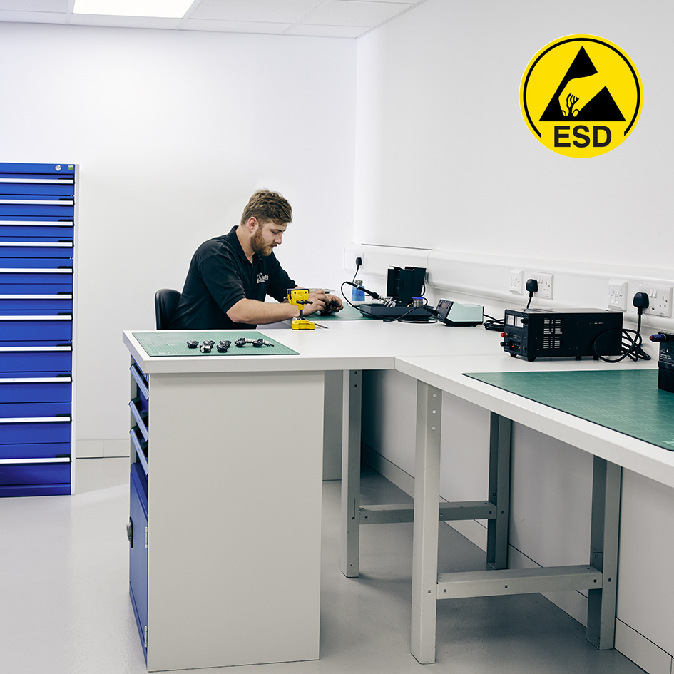 Man working at warehouse storage bench with ESD laminate worktops.