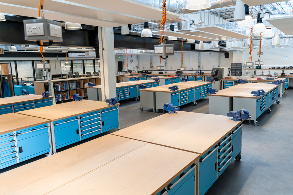 Rows of workplace storage benches with multiplex worktops in an education environment.